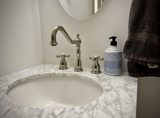 Elegant bathroom sink with a marble countertop and chrome faucet, next to soap dispenser, showcasing a clean water filtration system setup.